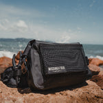 Black waterproof fishing bum bag on the beach featuring the missing at sea pliers 