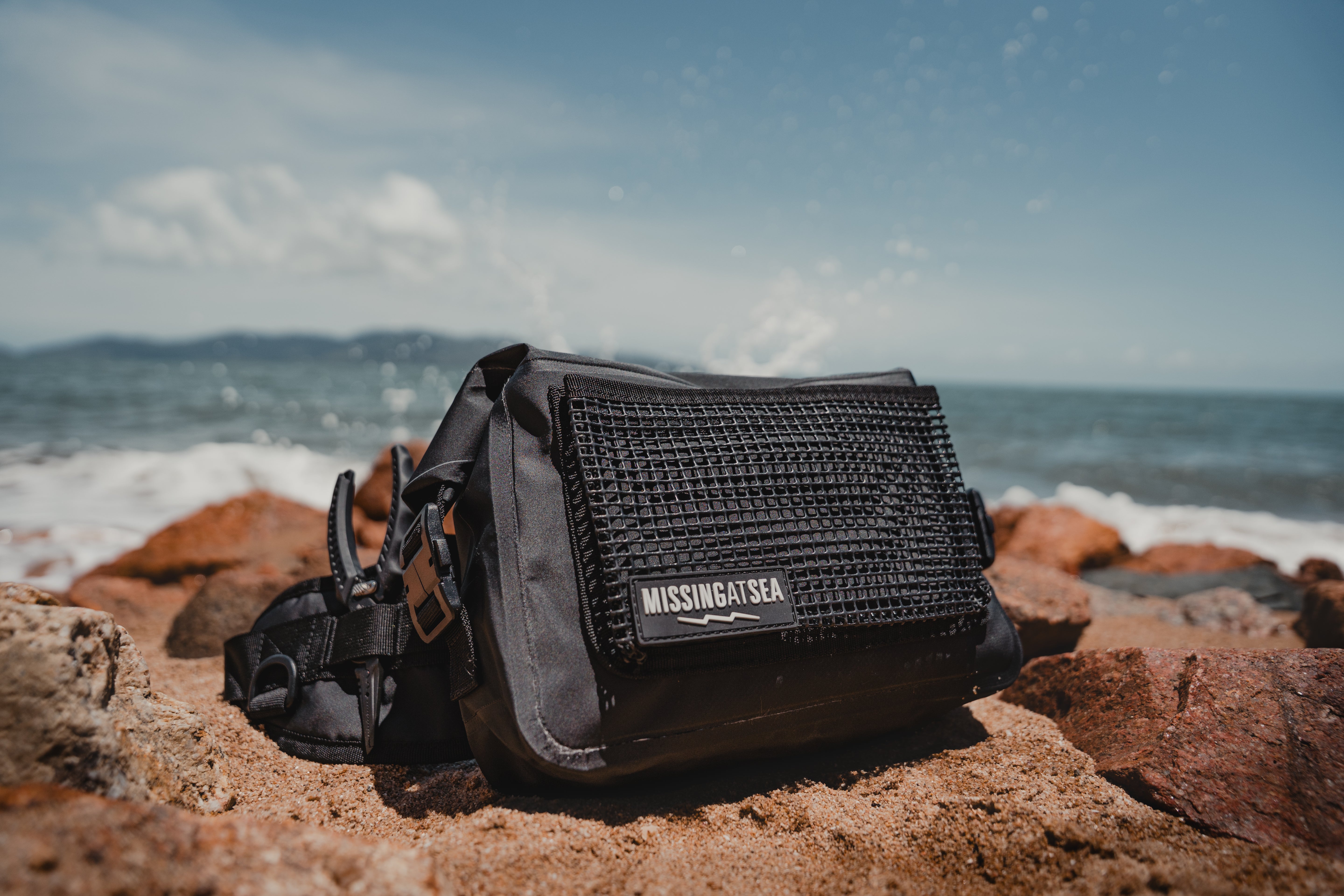 Black waterproof fishing bum bag on the beach featuring the missing at sea pliers 
