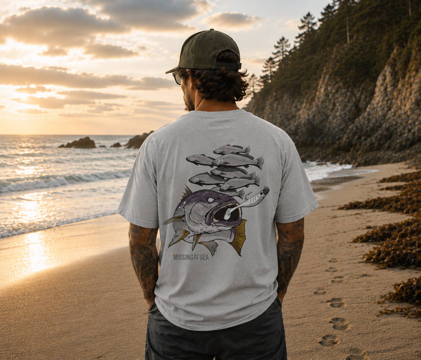 Man standing on a beach at sunset wearing a t-shirt with fish design